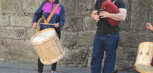 Pessoas a tocar música na rua, um homem a tocar gaita de foles e uma rapariga a tocar tambor