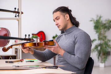 Young male repairman repairing violin