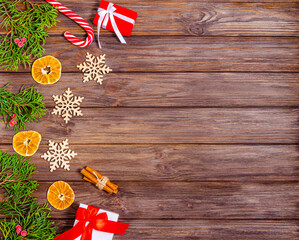 Christmas or New Year wooden background with Christmas tree decorations, orange slices, caramel, gift boxes and juniper branches.