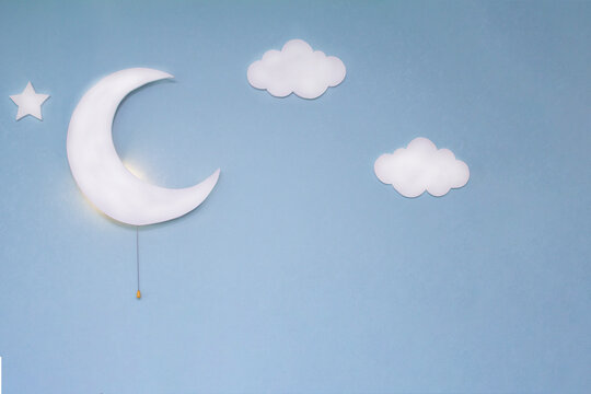 Night Light In The Shape Of A White Moon In The Children's Room With Additional Decor.