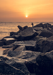 Fisherman at Sunrise Pulling in a Fish on His Line