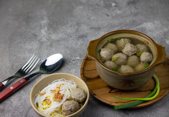 Bakso Sapi or Meatball traditional popular street food in Indonesia, served with clear soup, and noodles. Grey wooden background. Selective focus, copy space. 