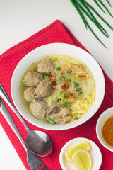 Bakso Sapi or Meatball traditional popular street food in Indonesia, served with clear soup, and noodles. Grey wooden background. Selective focus, copy space. 
