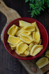 Buah Nangka or Jackfruit, one of tropical fruits popular in Indonesia. Cut into  half on red bowl and the seeds at behind. Dark wooden background. 