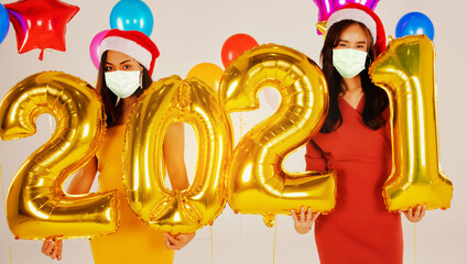 Buddy photo of a beautiful Asian woman celebrating the New Year holding a 202 gold number balloon and wearing a Covid-19 epidemic prevention mask during the festive season : Selective Focus