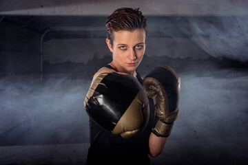 Closeup image of a female boxer punching with boxing gloves and looking at the camera