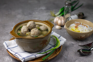 Bakso Sapi or Meatball traditional popular street food in Indonesia, served with clear soup, and noodles. Grey wooden background. Selective focus, copy space. 