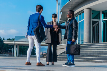 Business partners greeting one another by shaking hands outside workplace