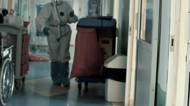 Hospital Worker Janitor In Full COVID-19 Protective Gown Equipment Cleaning Hallway