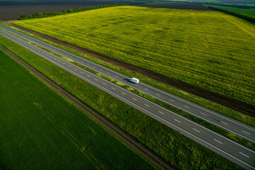 white van driving on asphalt road along the green fields. seen from the air. Aerial view landscape. drone photography.  travel concept