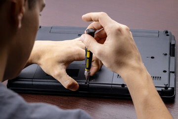 laptop repair service concept. man repairing or upgrading laptop hardware. person using screwdriver...