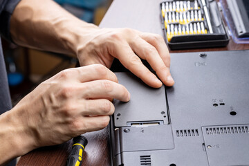 laptop repair service concept. man repairing or upgrading laptop hardware. person using screwdriver...