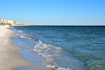 View of the Gulf Coast from the shore, green ocean, wave and wet sand, blue sky