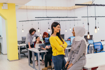 Portrait of two African American businesswomen talking to each other while standing in a modern...