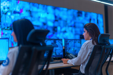 Group of Security data center operators (administrators) working in a group at a CCTV monitoring...