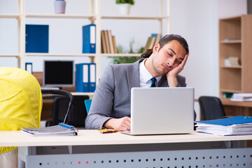 Young male employee looking after newborn at workplace