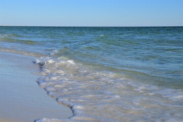Ocean green wave, white wave foam and wet beach sand, close up