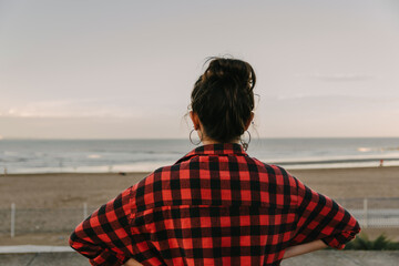 Fototapeta na wymiar Young beautiful brunette woman with red plaid shirt casual sea background, outdoor in the city, fashion concept, happy woman, copy space, social media, urban style