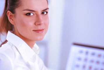 Attractive businesswoman sitting on a desk with laptop in the office