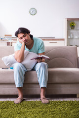 Young male student being tired preparing for exams at home