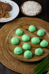 Klepon Rice Ball cake ready to boil, Klepon is Indonesian traditional sweet boiled cake, made from glutinous rice flour, pandan leaves, grated coconut, and palm sugar. Dark wooden background 