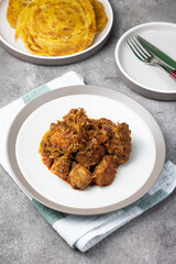 Ayam Kari or chicken curry, Indonesian traditional food served on ceramic plate, very popular at hari raya celebration food with roti canai, lontong, buras and ketupat. Grey wooden background.