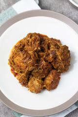 Ayam Kari or chicken curry, Indonesian traditional food served on ceramic plate, very popular at hari raya celebration food with roti canai, lontong, buras and ketupat. Grey wooden background.
