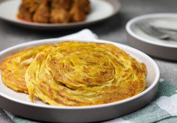 Roti Canai, traditional food popular in Indonesia during hari raya celebration, usually served with chicken curry or beef curry. Clode up view on Grey grainy background.