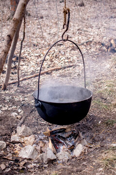  A large iron kettle is boiling off maple sap into maple syrup over an open fire 