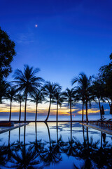 silouette swimming pool with sunbed and coconut tree at seaside resort
