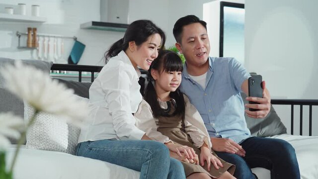 Asian young family making video call conference with their grandparent