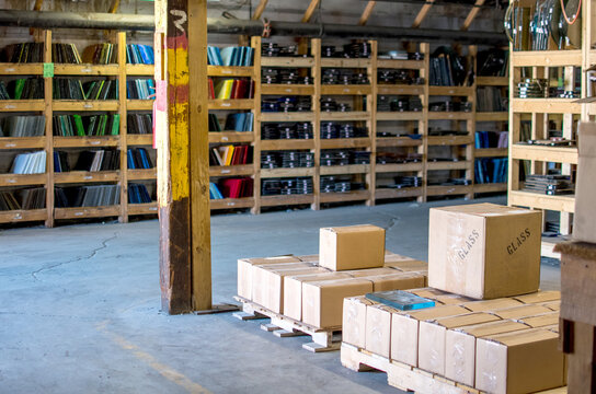 Boxes Of Glass Ready To Ship In A Glass Factory, With Many Colors Of Stained Glass On Wood Shelves 