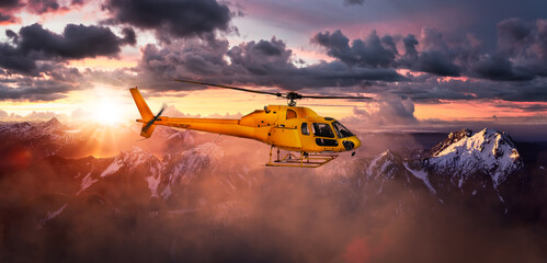 Yellow Helicopter flying over the Rocky Mountains. Dramatic Sunrise. Aerial Landscape from British...
