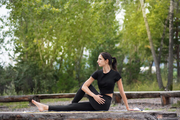a woman in a black suit does yoga in nature