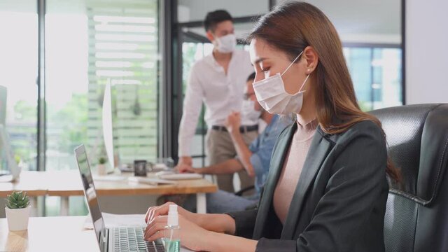 Asian businesswoman wearing face mask working on computer in office