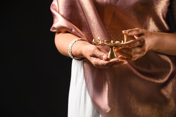 Woman holding diya lamp for celebration of Divaly on dark background, closeup