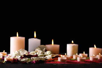 Burning candles and flower petals for celebration of Divaly on dark background