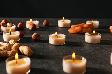 Burning candles with treats for celebration of Divaly on dark background