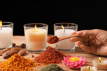 Female hand with spices and burning candles for celebration of Divaly on table
