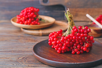 Plate with fresh viburnum berries on table
