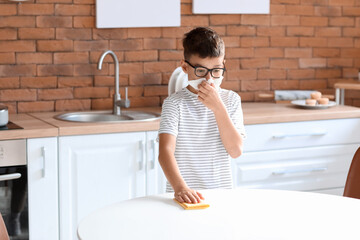 Little allergic boy cleaning kitchen