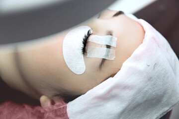 Eyelash Extension Procedure. Woman Eye with Long Eyelashes. Beautiful young girl eyelash extensions.