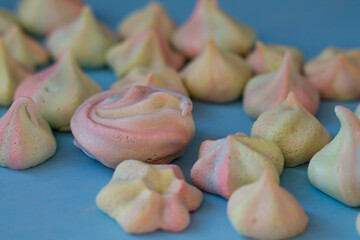 Colored meringues on a blue background. Delicious sweets with your own hands. A lot of sweets.