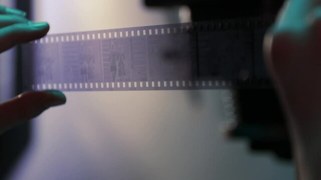Teenage girl reviewing film negatives in darkroom.