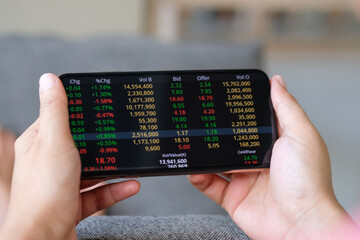 A woman using a smartphone checks the stock market . Concept of Technology and Investment