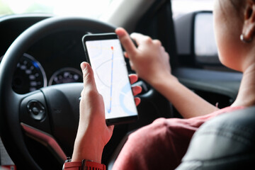 A woman car driving on the road And she is looking for a GPS map on a smartphone to get to the destination of the route. Concept of technology and road traffic