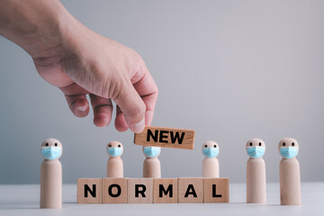 NEW NORMAL, disruptive innovation way of post covid-19 coronavirus pandemic concept, wooden doll wear Face mask with word " NEW NORMAL" on wood blocks.