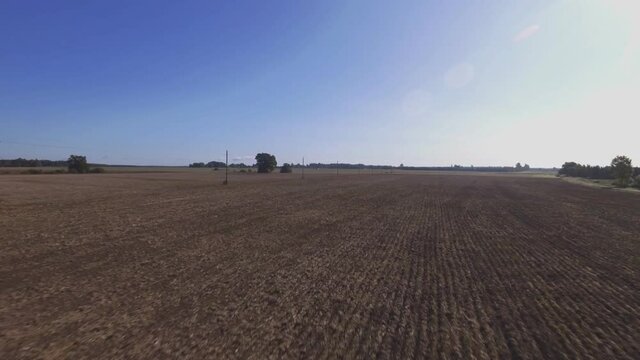 Power Supply Pole Lines In Harvested Agricultural Fields. Aerial Flying Backwards