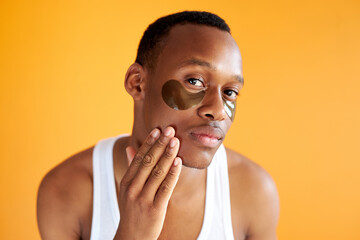 portrait of handsome afro american guy with patches for dark circles under eyes, young male do beauty procedures in the morning
