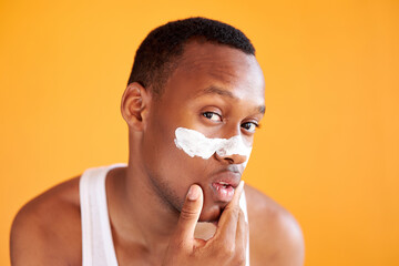 young afro american man apply mask on nose, get beauty procedures alone, enjoy morning. isolated yellow background